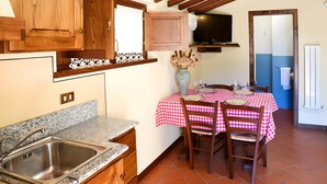 Une cuisine dotée d’un plan de travail en granit, de meubles en bois, d’une table à manger recouverte d’une nappe à carreaux et d’un vase rempli de fleurs.