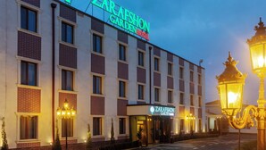 Un hôtel à plusieurs étages, reconnaissable à son enseigne bien visible indiquant : « ZARA FASHION GARDEN HOTEL ».