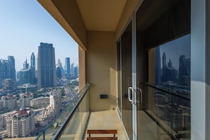 A balcony with a city view, a glass door, and a bench. - Abi Holidays Dubai Mall Fashion Avenue  (Dubai)