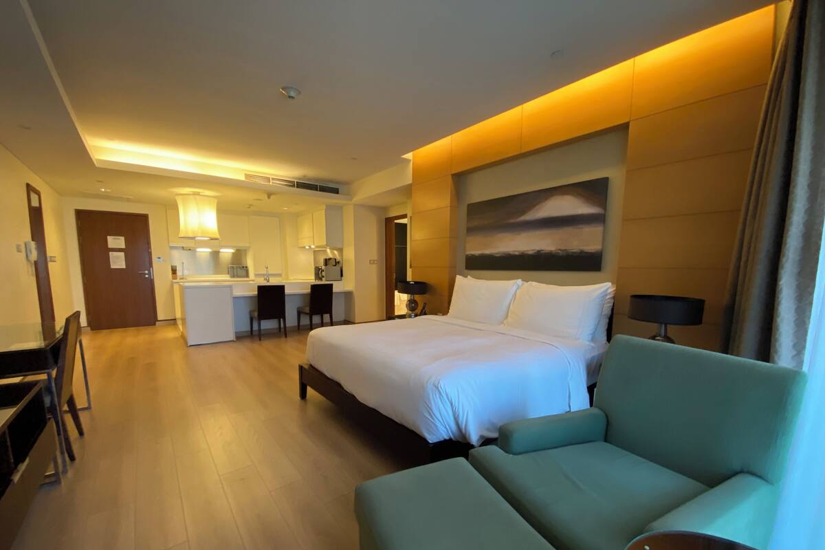 Ein Hotelzimmer mit Bett, einer Couch, einem Schreibtisch und einer Küchenzeile.
