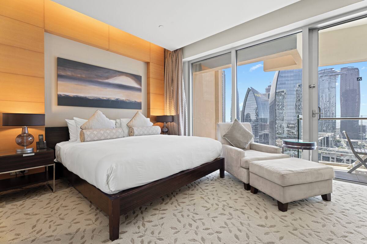 Ein modernes Hotelzimmer mit einem großen Bett, einer Couch und Blick auf die Stadtlandschaft.