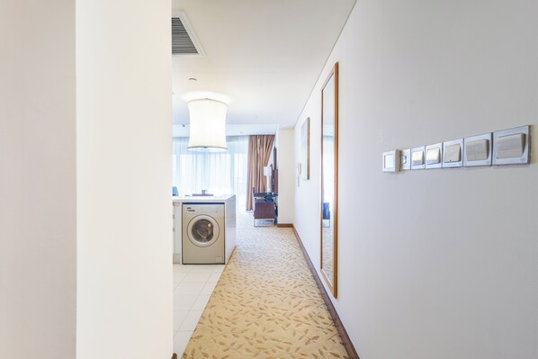 A hotel hallway with a washing machine, a large mirror, and framed pictures on the wall. - Abi Holidays Dubai Mall Fashion Avenue  (Dubai)