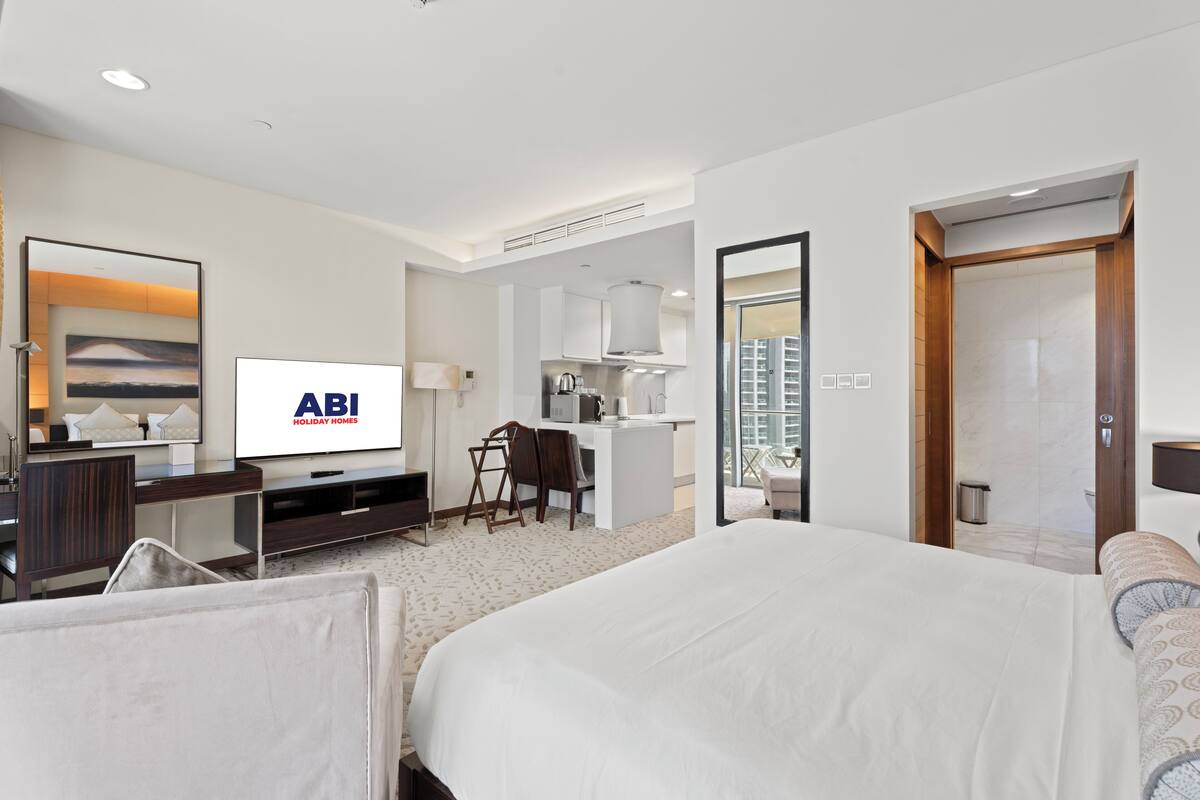 Ein Hotelzimmer mit einem großen Bett, einem Schreibtisch mit Stuhl, einem Fernseher und Blick auf die Stadt.