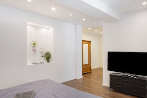 A modern bedroom with a bed, a TV, a dresser, and a mirror.