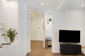 Un salon moderne avec un téléviseur à écran plat, un banc en bois et une plante en pot.