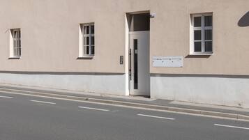 Un bâtiment à la façade beige, avec une porte blanche et une petite fenêtre sur laquelle est apposé un panneau indiquant le numéro « 4 ».