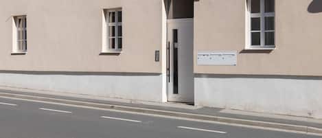 A building with a beige facade, a white door, and a small window with a number '4' sign above it.