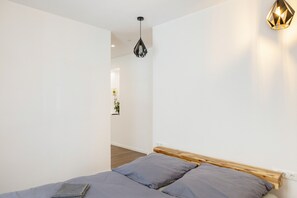 A bedroom with a bed, a wooden headboard, a hanging light fixture, and a wall-mounted light. - Buda Apartment with Private Terrace and Wi-Fi (Bad Kissingen)