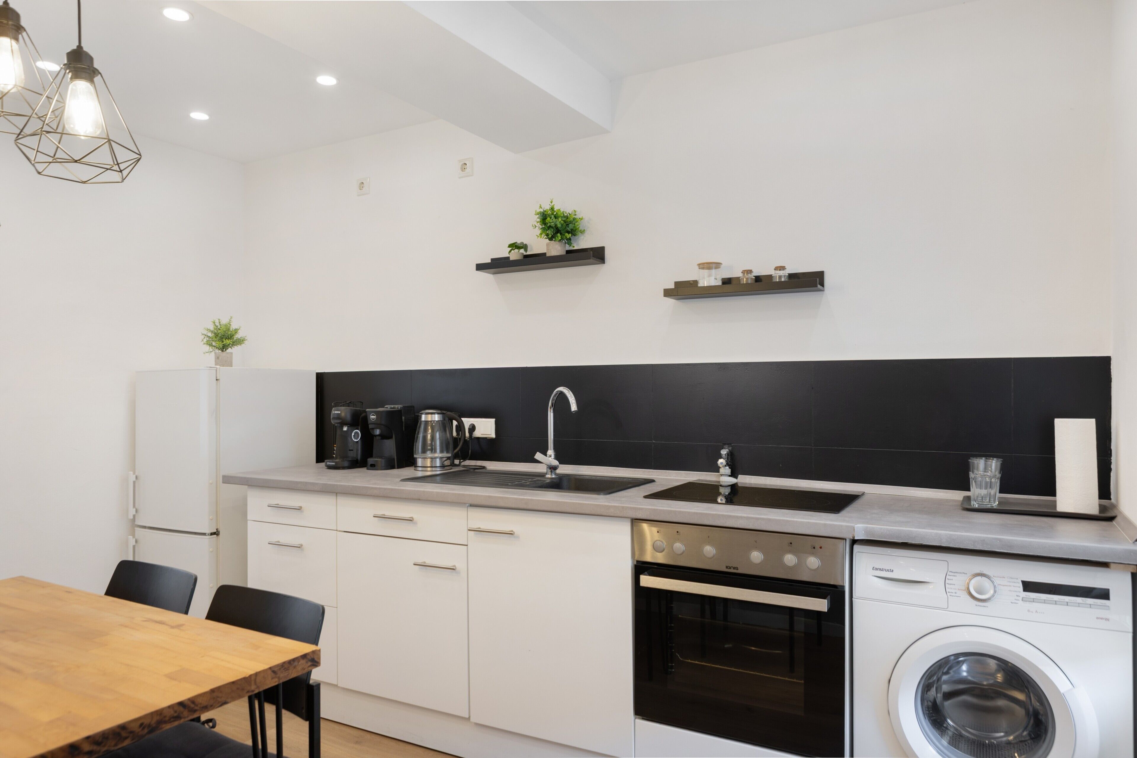 Een moderne keuken met een inbouwoven, vaatwasser en koffiezetapparaat.