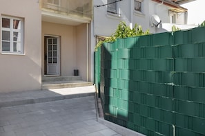A narrow pathway leading to a building entrance with a green metal fence and a door.