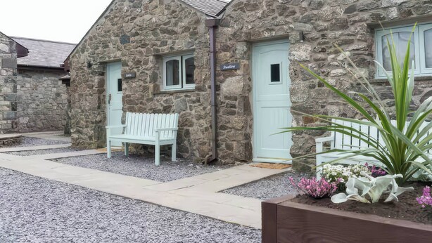 A stone building with a white bench and a door labeled "Swillow." - Black Bird Cottage (Gaerwen)