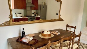 Uma mesa de jantar com cadeiras, um espelho e uma cozinha visível no reflexo.
