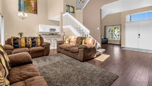 A spacious living room with a brown leather sofa set, a large rug, and a staircase leading to an upper level. - Upstay Home w Pool Hot Tub Patio - Pet Friendly (Kissimmee)