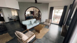 Uma sala de estar moderna com sofá, poltrona, mesa de centro e um espaço de jantar com televisão.