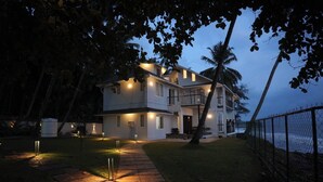 Uma casa de dois andares com varanda, um caminho que leva à entrada e vista para o oceano.