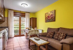 A living room with a sofa, a table, and a kitchen area with a window. - Rural Apartments La Viña (Apartment number 7) (Cangas de Onis)