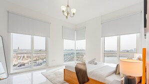 Moderni hotellihuone, jossa on suuret ikkunat, sänky, yöpöytä ja lamppu.