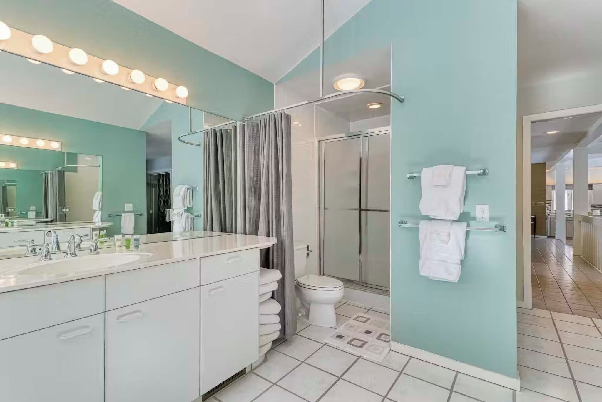 A modern bathroom with a large mirror, vanity, and a shower area.