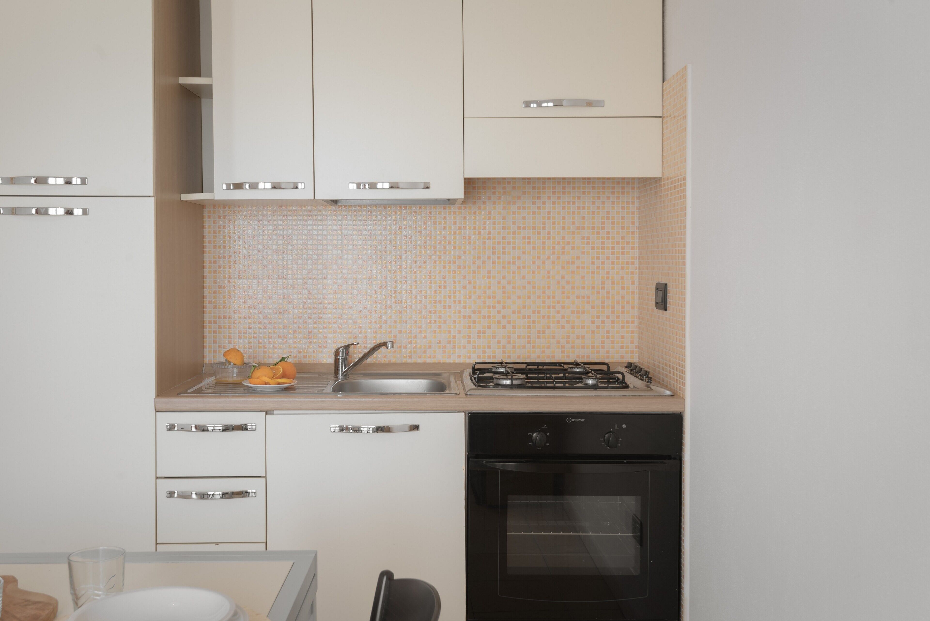 A compact kitchen with white cabinets, a sink, a stove, and a dishwasher.