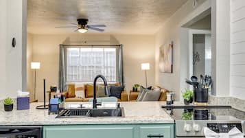 A kitchen with a granite countertop, a dishwasher, a stove, and a ceiling fan.