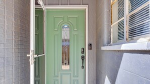 A green door with a window, a doorbell, and a mail slot.