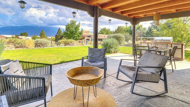 An outdoor patio with wooden furniture, a round wooden table, and hanging lanterns.