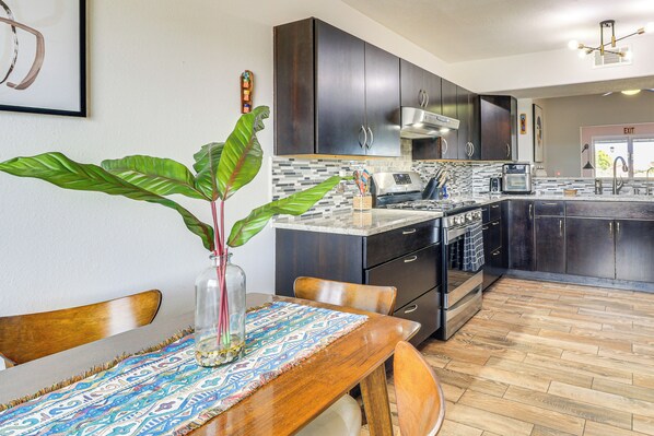 A modern kitchen with dark cabinets, a tiled backsplash, and a central island.
