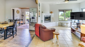 A spacious living room with a fireplace, a dining area with a wooden table and chairs, and a television on a wooden stand.