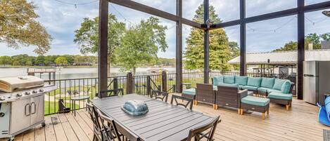 A covered outdoor deck with a grill, dining table, and seating area.