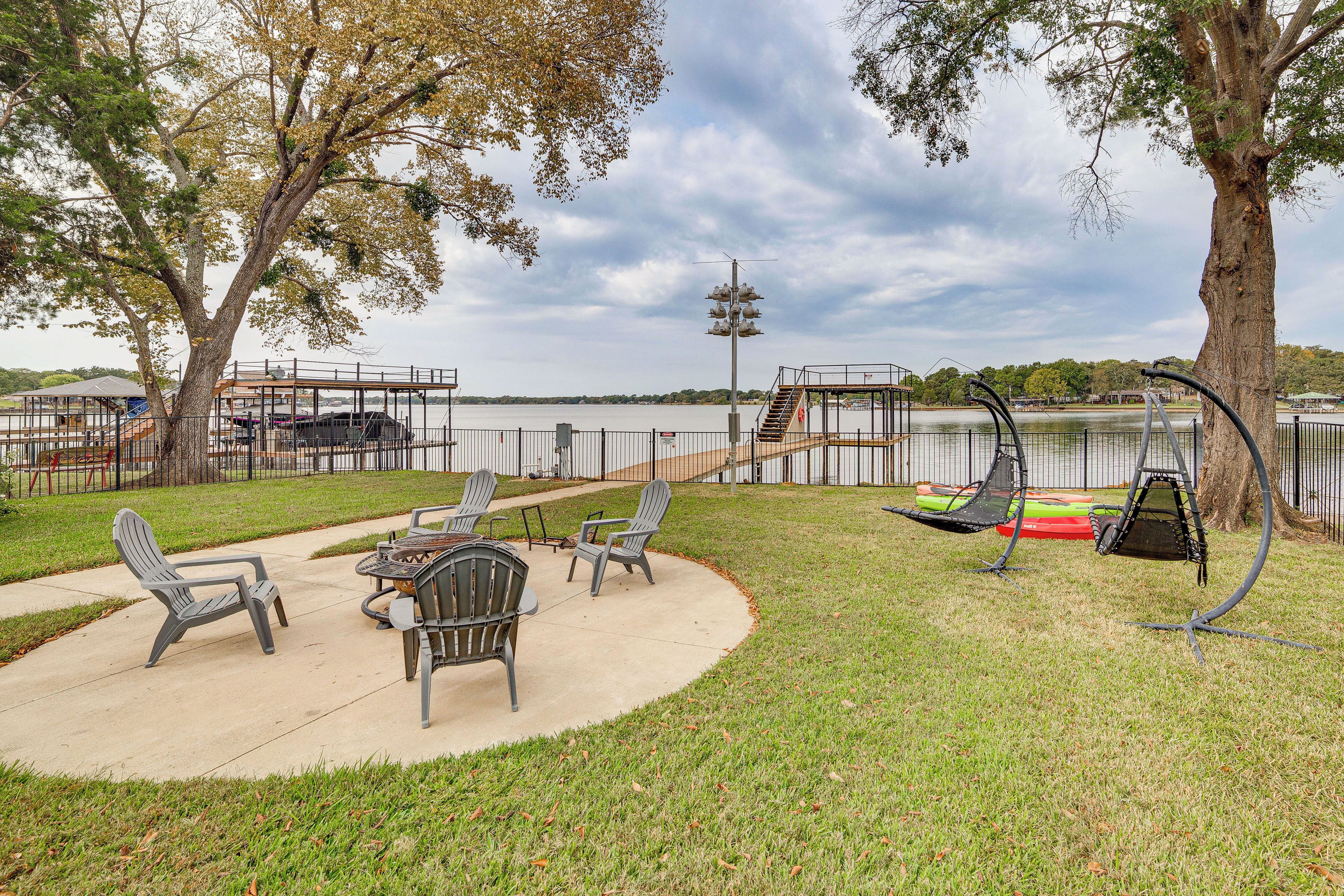 Un patio con mobiliario exterior, una hamaca y vistas a un lago.