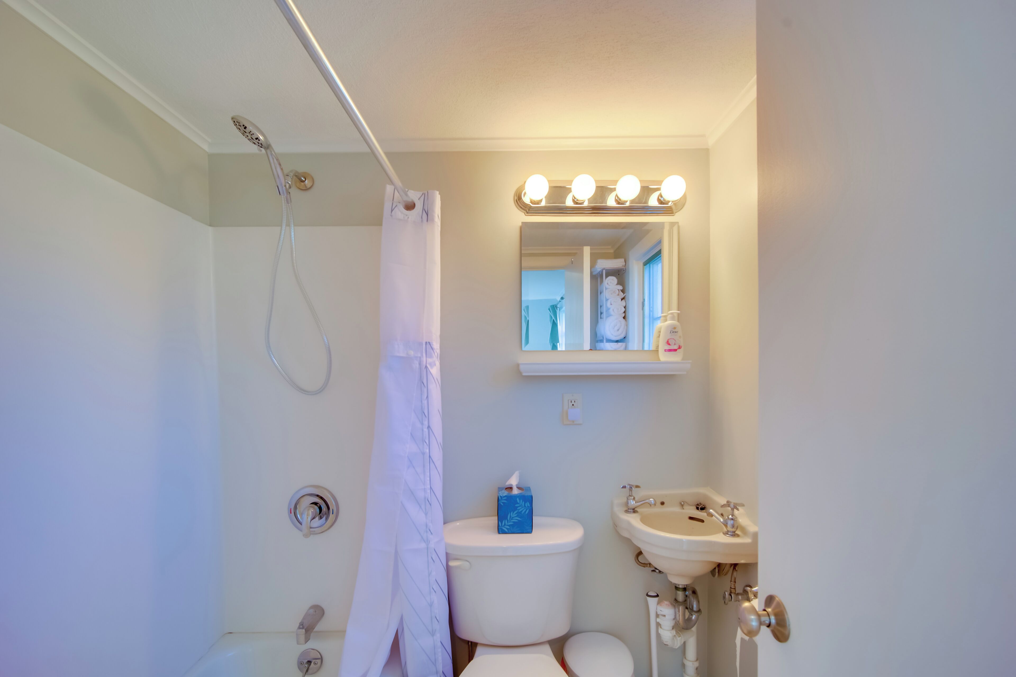 Une salle de bain équipée d’une douche, de toilettes, d’un lavabo et d’un miroir avec éclairage.