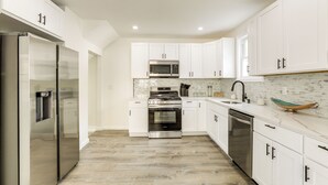 A modern kitchen with white cabinets, stainless steel appliances, and a tiled backsplash. - Private Yard! East Jersey Hub By River & Soccer! (National Park)