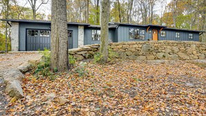 A rustic cabin with a stone wall entrance, surrounded by trees and autumn leaves. - Serene Getaway w/ Trail Access in Chester Springs (Chester Springs)