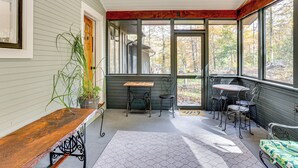 A covered porch with a wooden bench, metal table, and chairs, overlooking a forested area. - Serene Getaway w/ Trail Access in Chester Springs (Chester Springs)