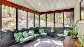 A sunroom with large windows, a wooden bench, and a table with a plant. - Serene Getaway w/ Trail Access in Chester Springs (Chester Springs)