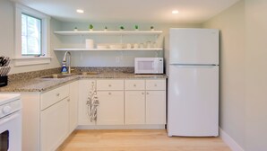 Eine moderne Küche mit weißen Schränken, einer Granitarbeitsplatte, einem weißen Kühlschrank und einer Mikrowelle.