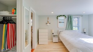 Ein Schlafzimmer mit Bett, Nachttisch, Kommode und Kleiderschrank mit Kleidung.