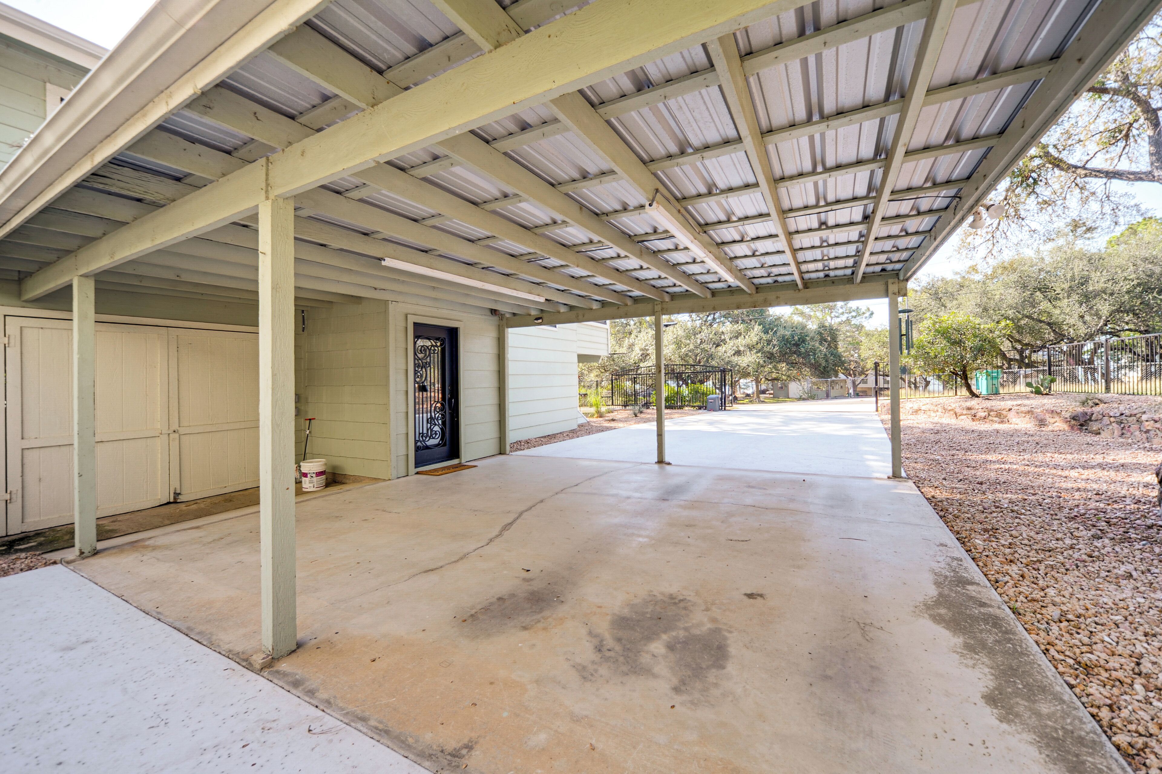 A covered outdoor area with a concrete floor, metal roof, and a door with a decorative handle.