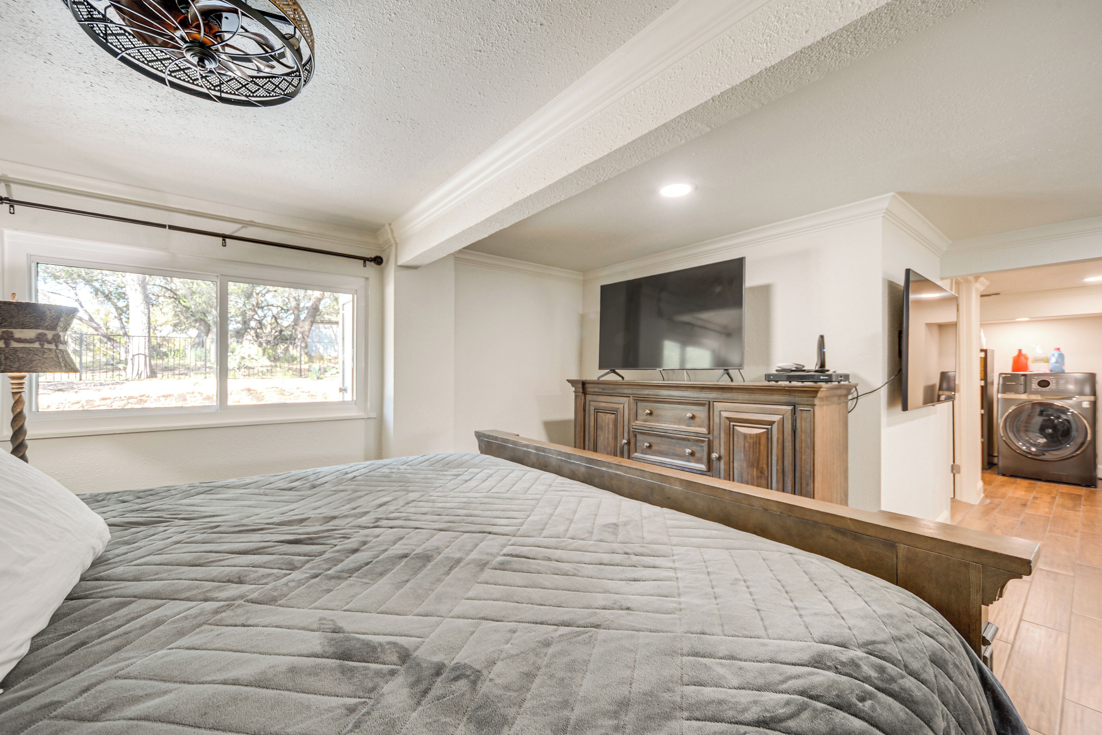 Une chambre à coucher avec un grand lit, une commode, un téléviseur et un lave-linge dans la pièce adjacente.