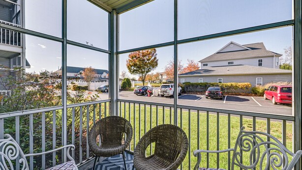 Un balcone coperto con sedie in vimini e vista su un parcheggio e case.