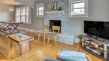 A living room with a fireplace, wooden furniture, a television, and a large window.