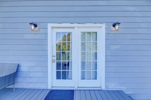Una casa con puerta blanca, dos luces empotradas en la pared y un porche azul con felpudo.