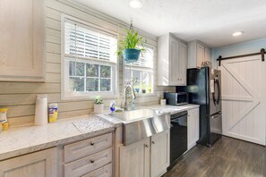 A kitchen with wooden cabinets, a stainless steel sink, a black refrigerator, and a hanging plant. - 'coastal Cozy' - Newport Home w/ Private Hot Tub (Newport)