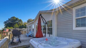 Ein Whirlpool mit einer Schwane als Schwimmnudel, ein Grill und eine Terrasse mit Stühlen und Sonnenschirm.