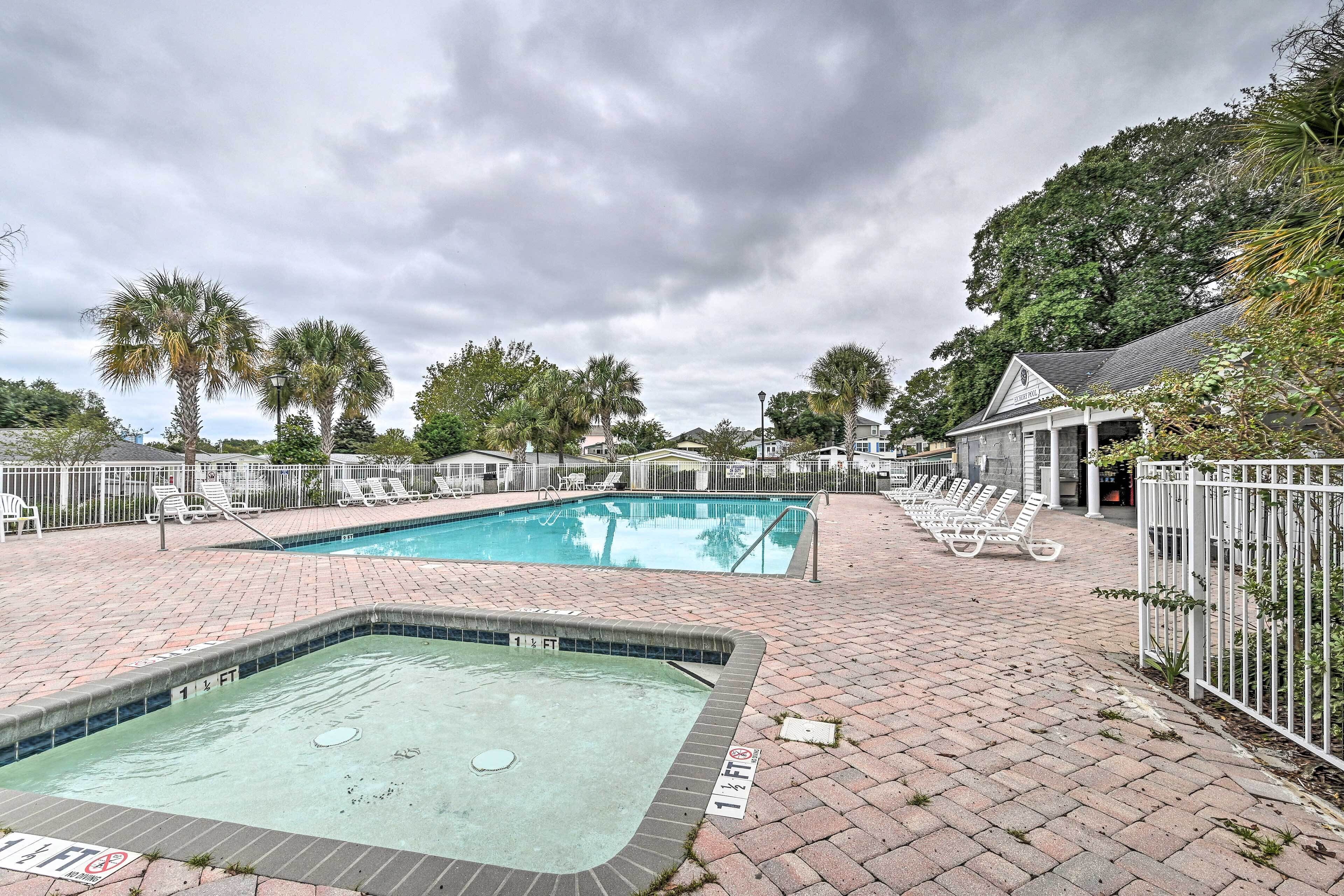 A swimming pool area with lounge chairs and a hot tub.