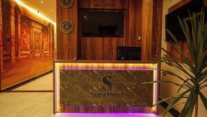 Een receptiebalie met een marmeren blad en een verlicht 'Sama Hotel' bord.