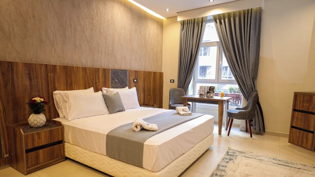 Een moderne hotelkamer met een groot bed, een bureau en uitzicht op de stad door het raam.