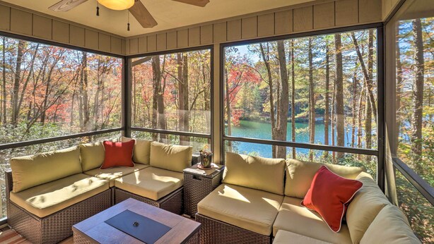 A sunroom with a view of a lake surrounded by trees. - Festive Lakefront Escape: Blue Ridge Holiday Home (Brevard)