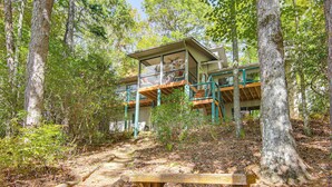 A cabin with a wooden deck and a bench, surrounded by trees. - Festive Lakefront Escape: Blue Ridge Holiday Home (Brevard)