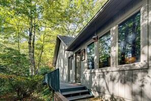 A wooden cabin with a porch, surrounded by trees. - Festive Lakefront Escape: Blue Ridge Holiday Home (Brevard)